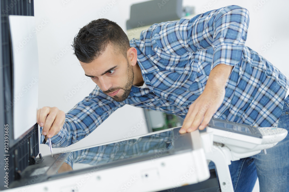 Obraz premium young male technician repairing digital photocopier machine