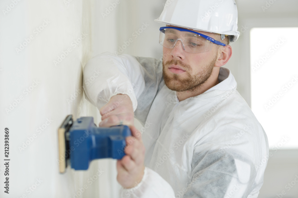 builder hand sanding interior wall for restoration