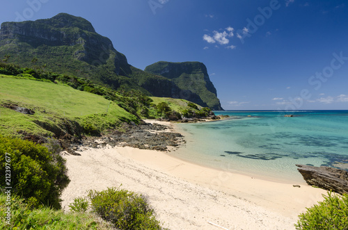 Beautiful, sandy beach in Lord Howe Island with Mounts Gower and Lidgbird in the background on a bright, sunny day.