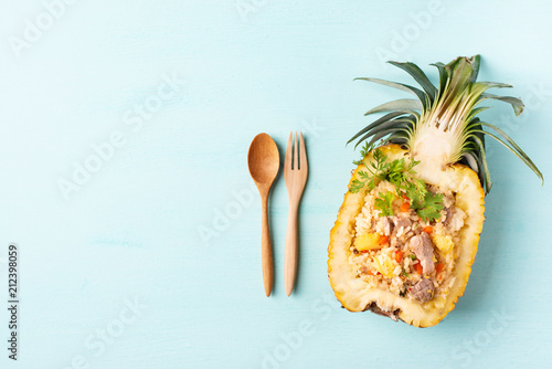 Fried rice with pork in half pineapple fruit on green background, Thai cuisine