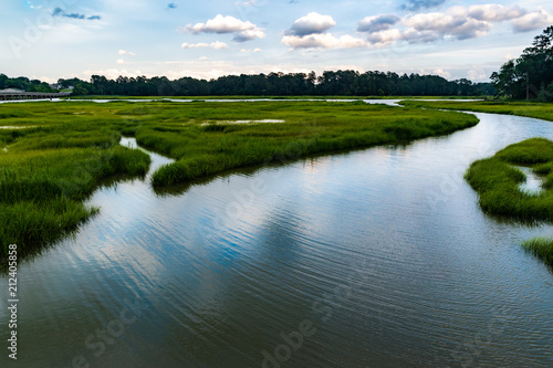 Wetlands river runs through reeds and into a coastal river underneath a dark and brooding sky
