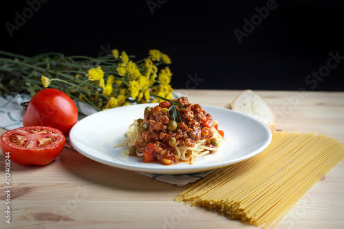 Italian spaghetti with a meat based sauce in a plain white plate on wooden table. Spaghetti pasta with tomatoes ketchup.