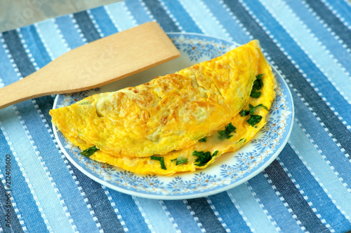 French omelette on a kitchen towel. French omelet from eggs, grated cheese and parsley on a saucer. Breakfast of eggs for a healthy diet.