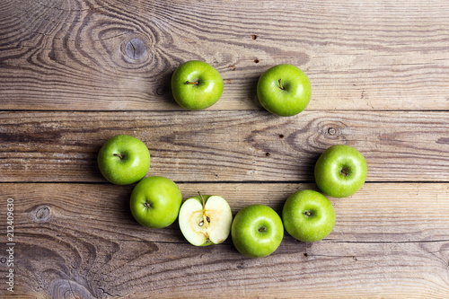 Smiling face of green apples on a wooden table. Apple emoticon.