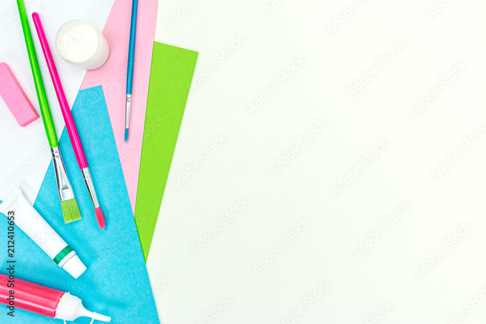 Fototapeta premium school desk with album paper, brushes, paints, eraser. school stationary on white desk background