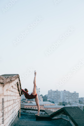 Young and graceful ballerina performing on roof of city building