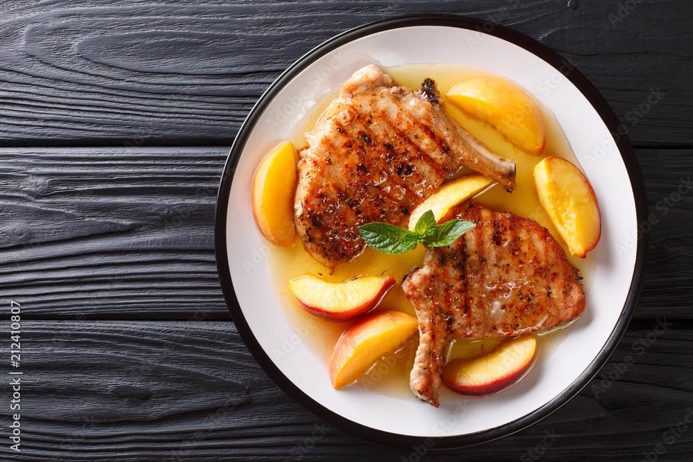 grilled pork chop with glazed peaches and honey garlic sauce close-up on a plate. horizontal top view from above