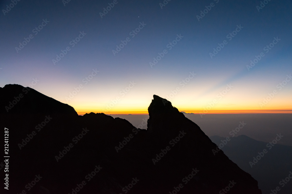 First Rays of Rising Sun in Orange Color at Top of Mount Agung Volcano. Bali, Indonesia