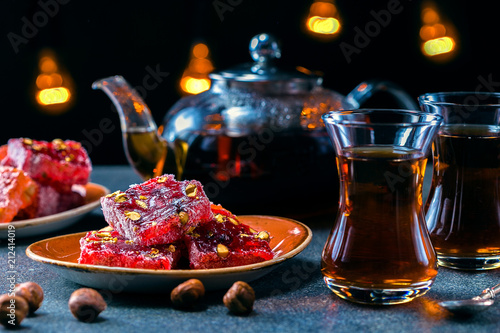 Turkish tea in traditional glass and plate with rahat lokum. Istanbul cafe with oriental culture of the street food.Evening time.