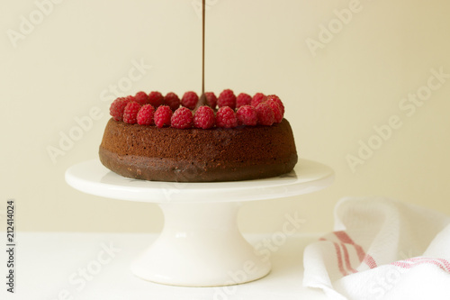 Chocolate brownie cake with raspberries and chocolate icing on a light background. photo