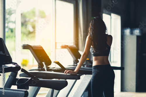 sport girl standing on the treadmill in the gym photo