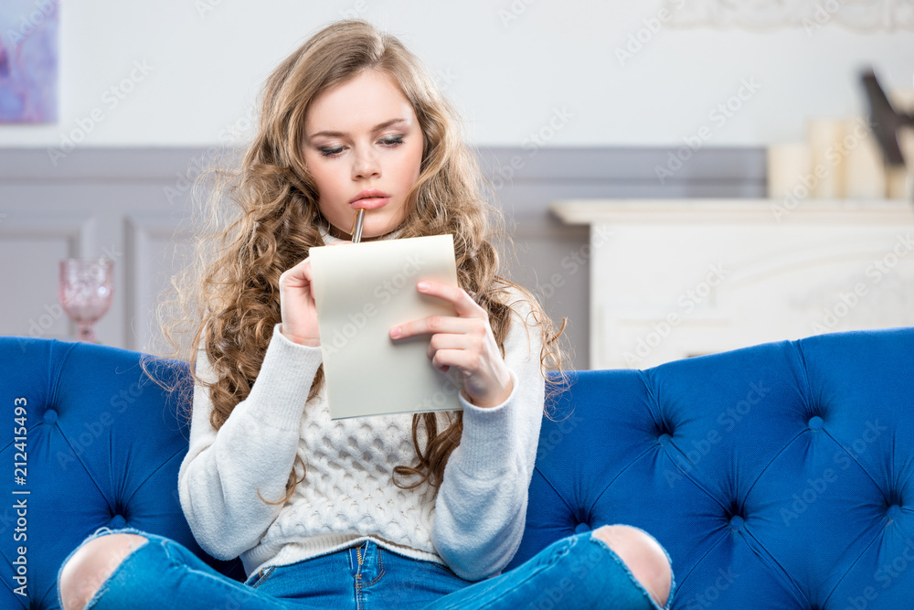 portrait of a pensive young girl with a sheet of paper sitting on the couch portrait of a pensive young girl with a sheet of paper sitting on the couch