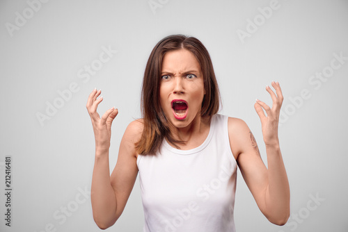 Angry woman looking at camera. Aggressive business woman standing isolated on white studio background. Female half-length portrait. Human emotions, facial expression concept. Front view.