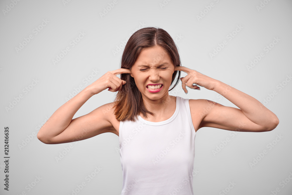 Negative human emotions, reaction and attitude. Frustrated annoyed girl with brunette hair plugging ears with fingers, feeling irritated with loud annoying noise, cant concentrate on work Negative human emotions, reaction and attitude. Frustrated annoyed girl with brunette hair plugging ears with fingers, feeling irritated with loud annoying noise, cant concentrate on work