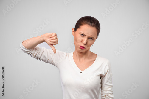 Wallpaper Mural Front view portrait of sad beautiful lady with bad job gesture and unhappy face looking at you on isolated studio. Hater woman with negative emotion showing thumb dislike down Torontodigital.ca