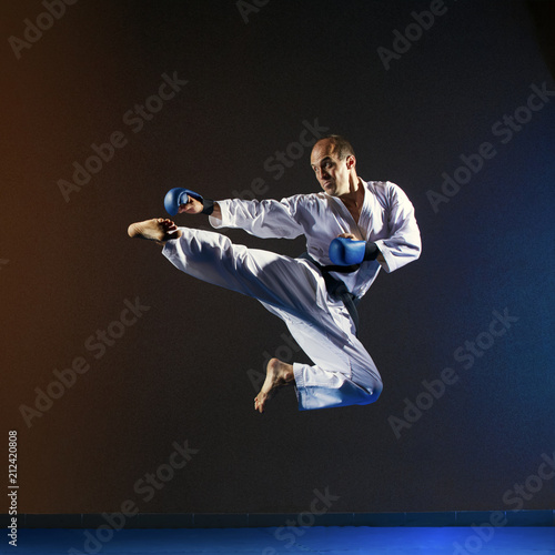In a high jump athlete in karategi trains a kick