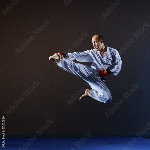 Sportsman beats kick leg in jump in a white karategi