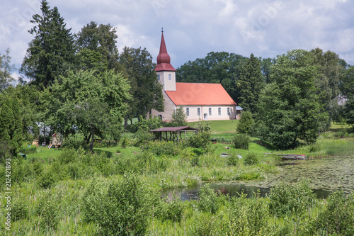 Lake and old church. Blue sky and green grass. photo