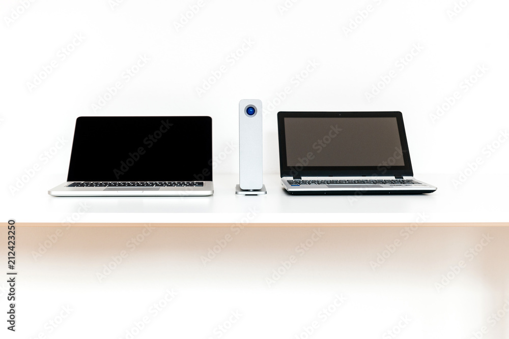 Two computers on table with portable HDD desk hard disk drive against white background Two computers on table with portable HDD desk hard disk drive against white background