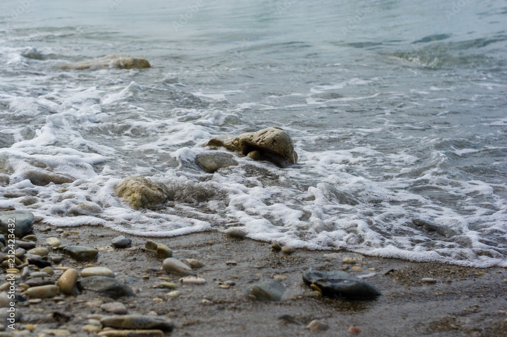 pebble stones on the sea beach, the rolling waves of the sea with foam pebble stones on the sea beach, the rolling waves of the sea with foam