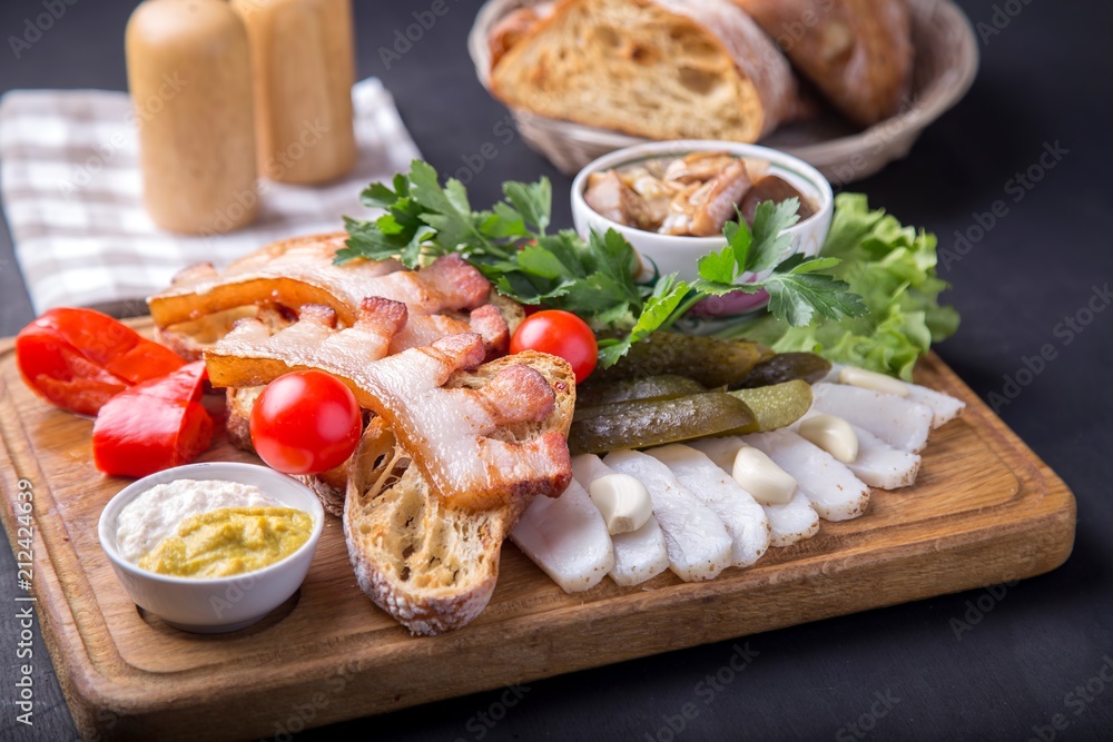 Snack with fried brisket, bread,  cut lard, fresh tomatoes and marinated mushrooms. Tasty appetizer on wooden board