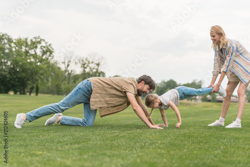 side view of happy family having fun on green grass in park