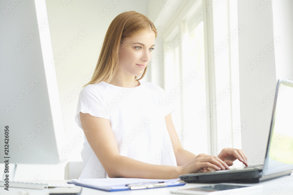 Young professional woman using laptop while working at home office Young professional woman using laptop while working at home office