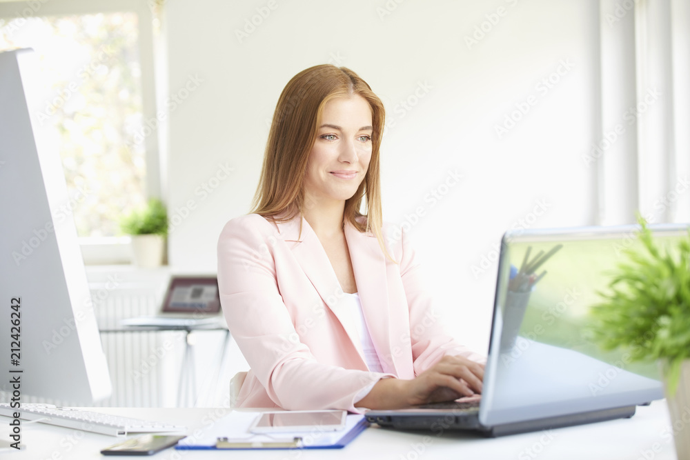 Young professional woman using laptop while working at home office Young professional woman using laptop while working at home office