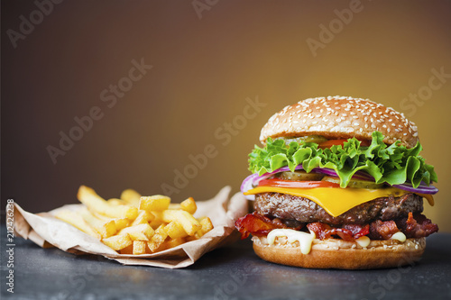 big cheeseburger with heap of french fries on slate board