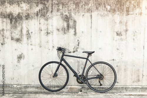 Matt black race road bike parked in front of grunge textured background with vintage tone. 