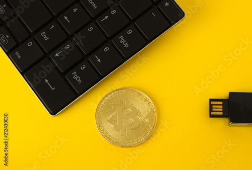 Golden bitcoin, keyboard and flash drive on a yellow background top view photo