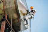 Industrial climber washing big barrel with water pressure. Risky job.