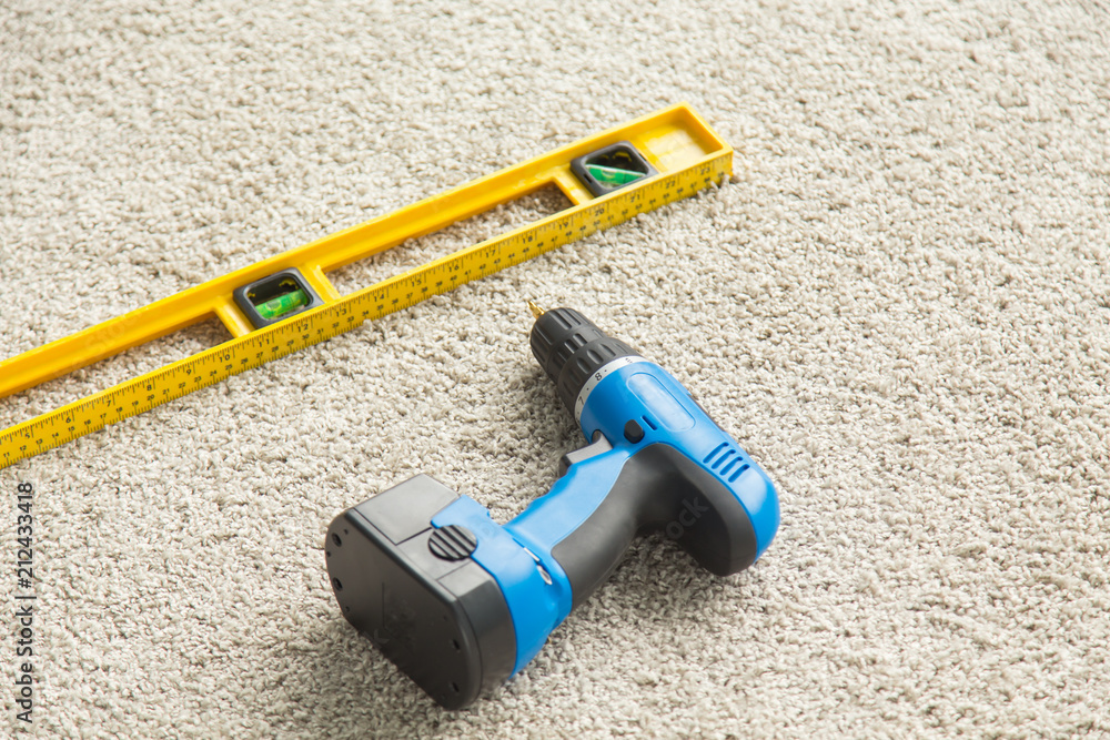 Builders level and drill on the floor, top view Builders level and drill on the floor, top view