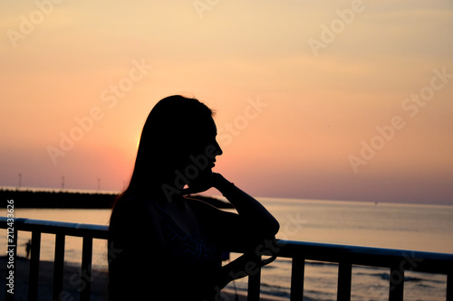 Silhouette of a beautiful girl at sea in the setting sun