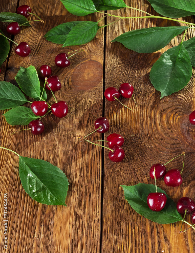 Groups of cherries with stems, branch with leaves on table Groups of cherries with stems, branch with leaves on table