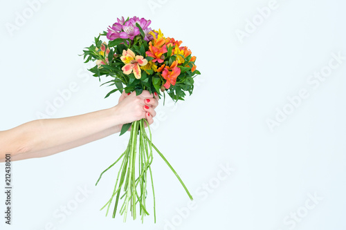 flowers and floristry. hands holding alstroemeria composition on white background. festive spring or summer gift bouquet on mothers day or birthday