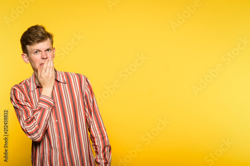 squeamishness aversion nausea repulsion. man is disgusted. portrait of a guy on yellow background. copyspace for advertisement. photo