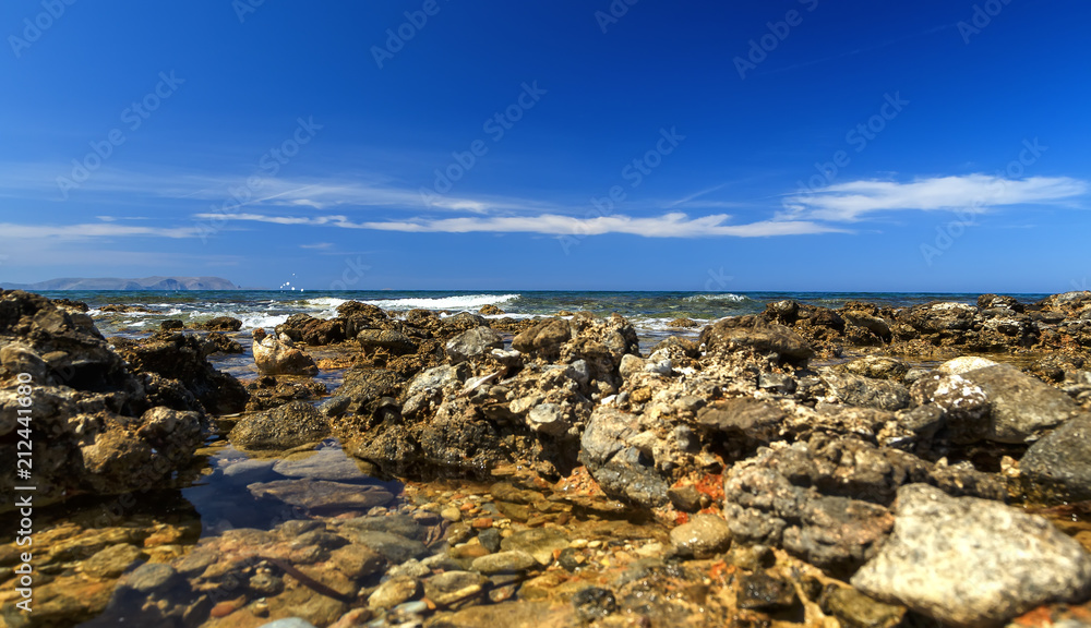 Summer trip to island of Crete, Greece. Rocky and stony coast. Dream view of the waves, rocks and deep blue sea. The Mediterranean coast.
