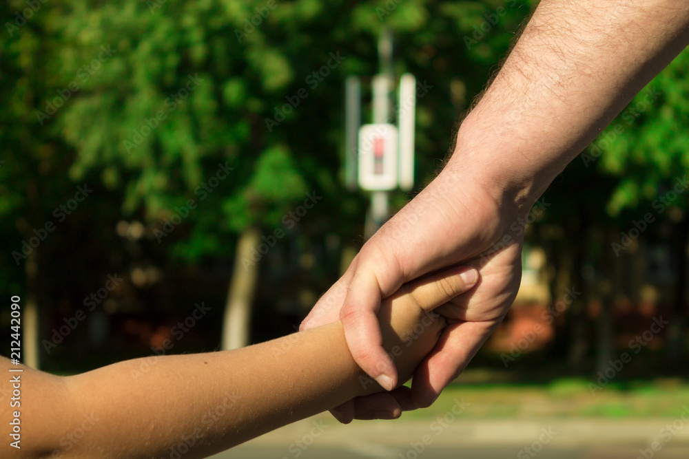 The concept of safety, child protection at a pedestrian crossing. Father holds his son's hand. The concept of safety, child protection at a pedestrian crossing. Father holds his son's hand.