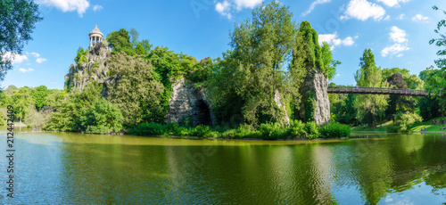 Photography Panoramic view of the park of Buttes-Chaumont in summer including the suspension bridge that faces the island