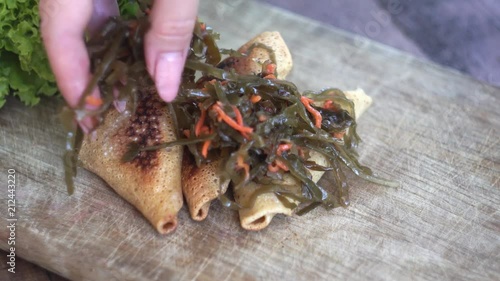 Pancakes stuffed with seafood and carrots, green lettuce leaves. Cooking. Clous-up photo