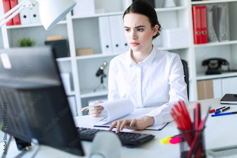 Young girl in the office working with documents at the computer.