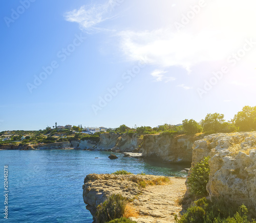 Waves break on rocky shore. Coast and beach resort village. Road along a rocky cliff. Tourist beach resort in village Crete island, Greece