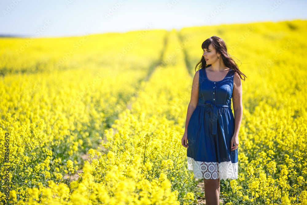 young happy beautiful big size model girl in blue dress on blooming rapeseed field in summer. young happy beautiful big size model girl in blue dress on blooming rapeseed field in summer.