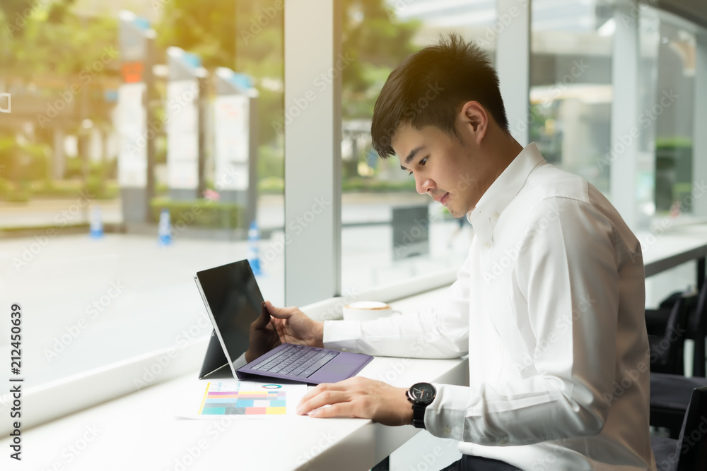 Handsome Asia businessman using laptop and analysis graph visualization at coffee shop Handsome Asia businessman using laptop and analysis graph visualization at coffee shop