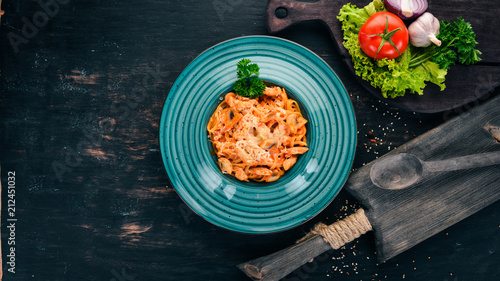 Pasta with chicken and mushrooms. Italian cuisine. On a wooden background. Top view. Copy space.