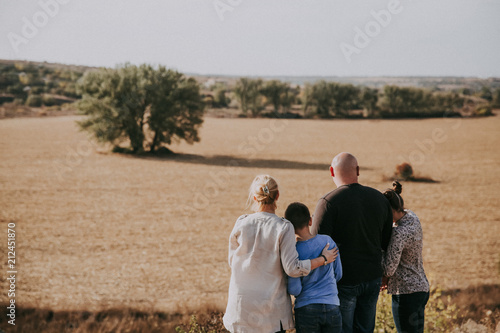 A happy family is standing in the nature at sunset i