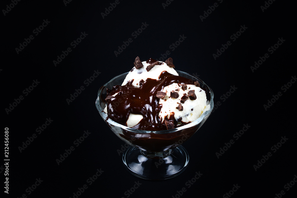 Vanilla ice cream in a white bowl with chocolate on a black background. Vanilla ice cream in a white bowl with chocolate on a black background.