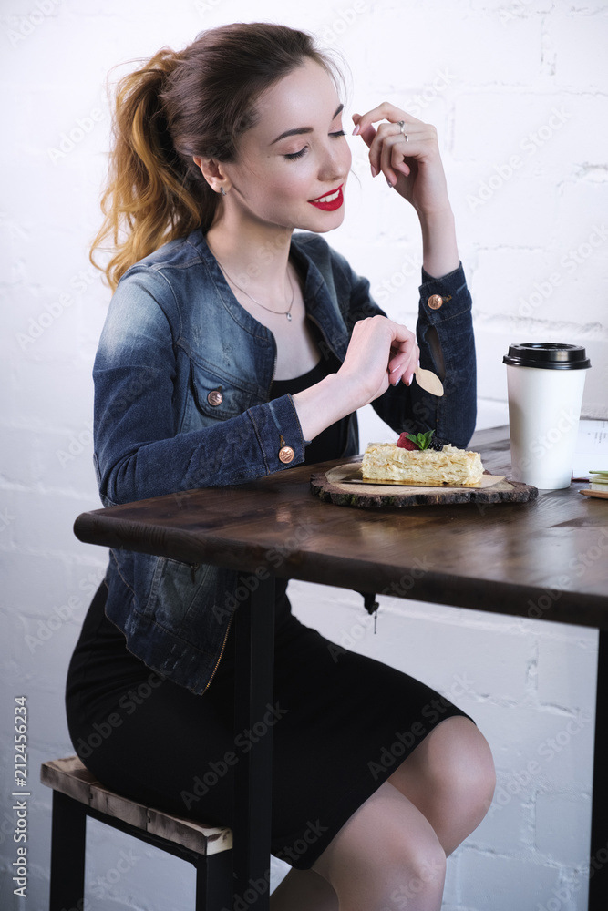 Girl with red lipstick on her lips sitting at a high table with cake and coffee. Girl with red lipstick on her lips sitting at a high table with cake and coffee.