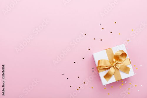 Gift or present box and stars confetti on pink table top view. Flat lay composition for birthday, mother day or wedding.